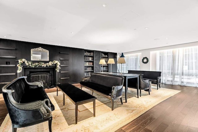 living area with built in features, recessed lighting, a fireplace, and wood finished floors