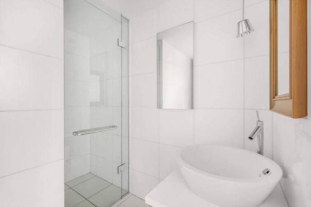 bathroom featuring tile walls, walk in shower, and sink