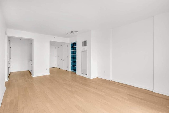 spare room with light wood-style flooring, rail lighting, baseboards, and visible vents