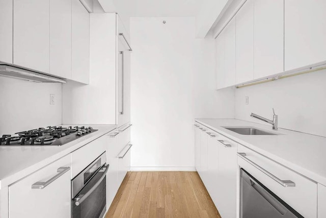 kitchen featuring white cabinetry, light countertops, appliances with stainless steel finishes, and a sink