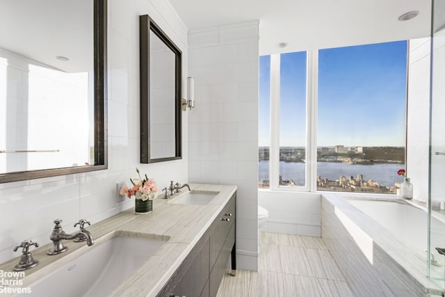 full bathroom with a water view, a tub, toilet, and a sink