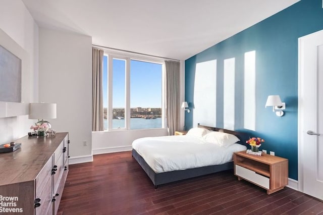 bedroom with a water view, dark wood-type flooring, and lofted ceiling