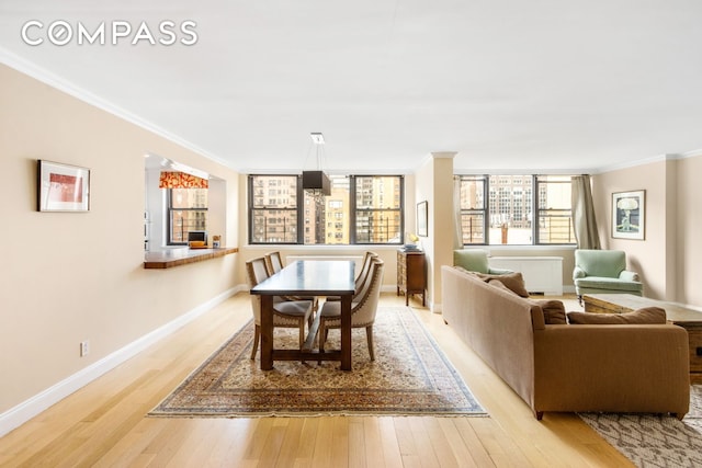 dining room with baseboards, light wood finished floors, and ornamental molding