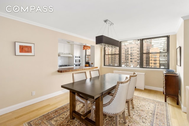 dining space with a healthy amount of sunlight, wood finished floors, baseboards, and ornamental molding