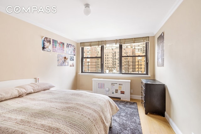 bedroom with baseboards, light wood-style flooring, and crown molding