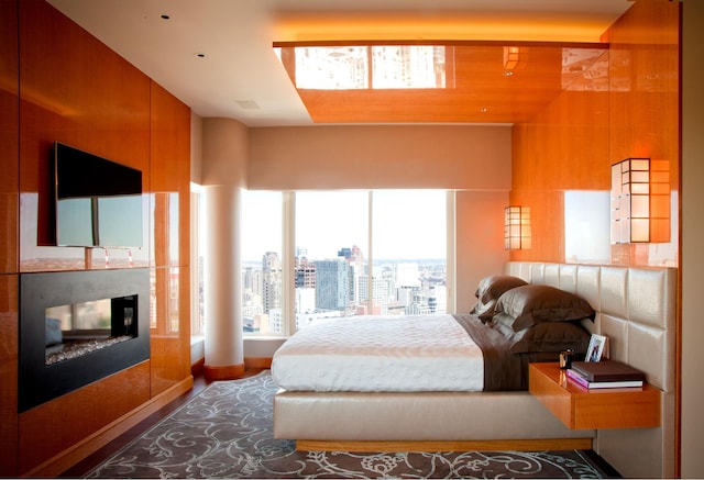 bedroom with wood finished floors, a multi sided fireplace, and baseboards