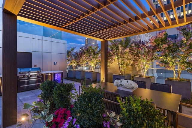 patio terrace at dusk with area for grilling and a pergola