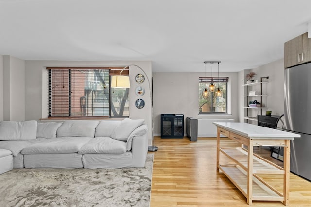 living room with an inviting chandelier, plenty of natural light, and light hardwood / wood-style flooring