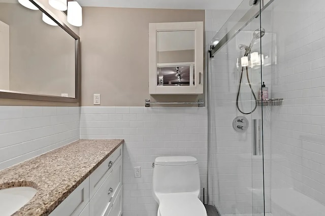 full bath featuring toilet, a wainscoted wall, vanity, tile walls, and a stall shower