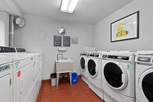 common laundry area featuring dark tile patterned floors, washing machine and clothes dryer, and baseboards