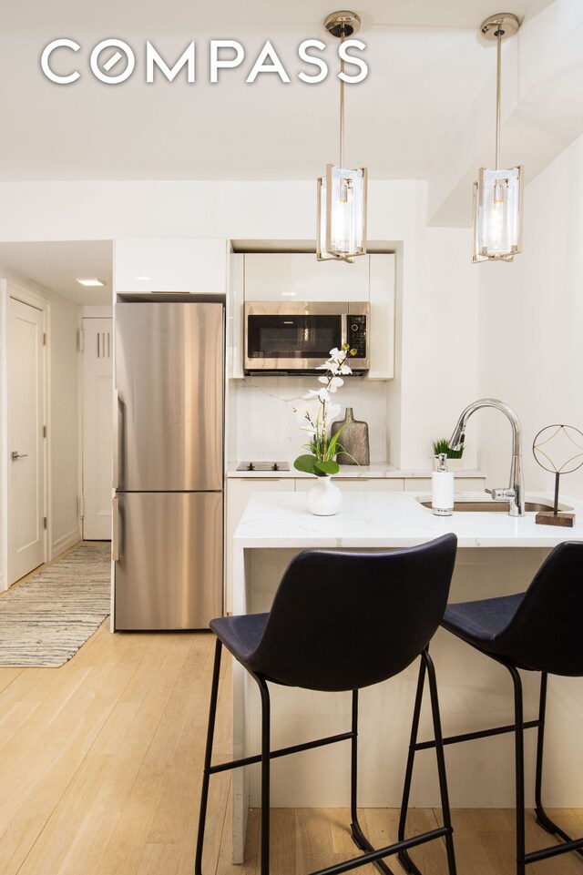 kitchen with light stone countertops, white cabinetry, appliances with stainless steel finishes, and decorative light fixtures