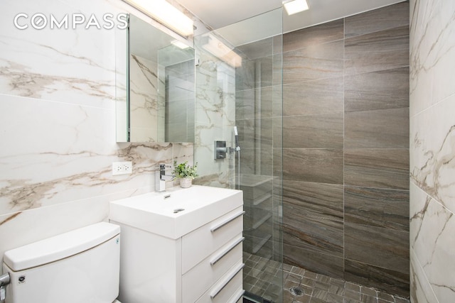 bathroom featuring a shower with door, vanity, and toilet