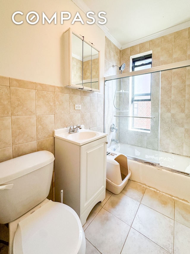 full bath with toilet, bath / shower combo with glass door, vanity, tile walls, and tile patterned floors