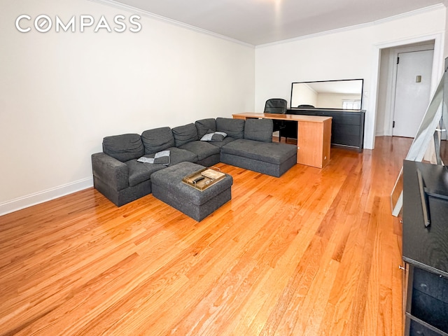 living room with light wood-type flooring, crown molding, and baseboards