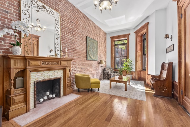 sitting room featuring hardwood / wood-style flooring, brick wall, and a notable chandelier