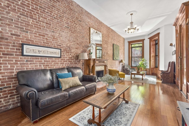 living room featuring a notable chandelier, brick wall, and hardwood / wood-style floors