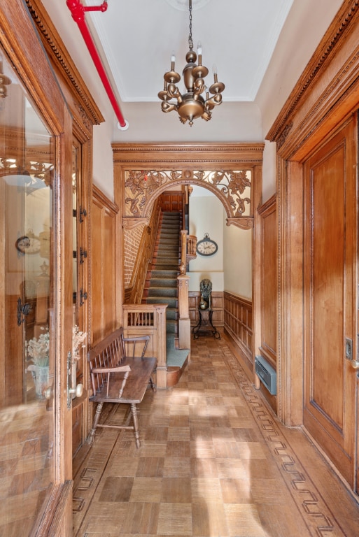 corridor featuring ornamental molding and an inviting chandelier