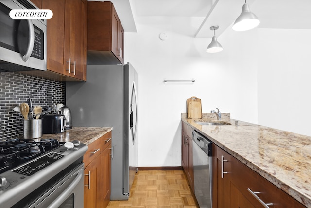 kitchen with a sink, stainless steel appliances, baseboards, decorative backsplash, and light stone countertops