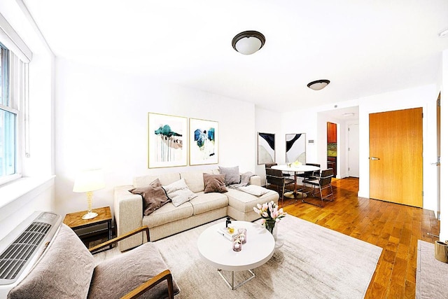 living room with hardwood / wood-style floors, plenty of natural light, and an AC wall unit