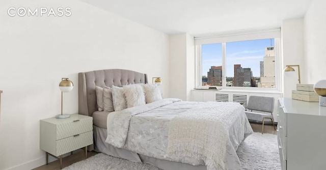 bedroom featuring a city view, baseboards, and wood finished floors