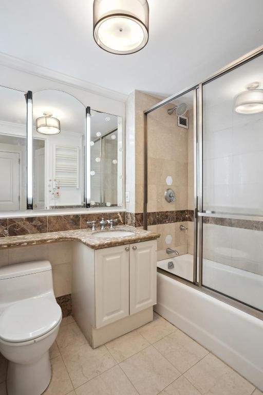 full bathroom featuring tile patterned flooring, enclosed tub / shower combo, tile walls, and vanity