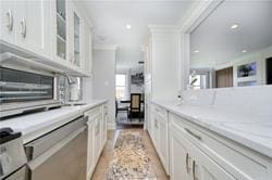 kitchen with light stone counters, a wealth of natural light, white cabinets, and crown molding