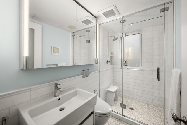 bathroom featuring toilet, an enclosed shower, sink, and tile walls