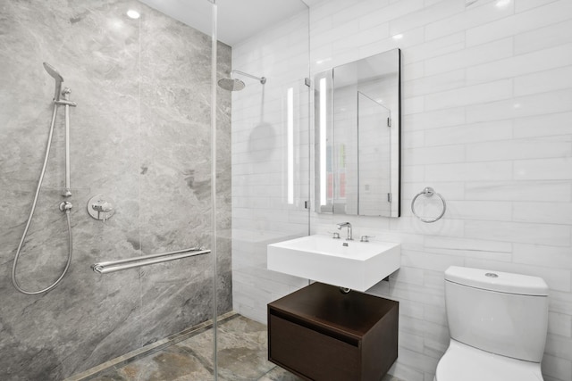 bathroom with toilet, tile walls, a sink, and tiled shower