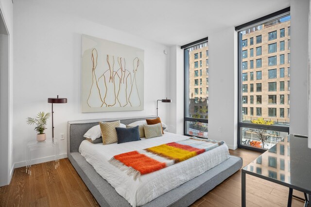 bedroom featuring expansive windows and hardwood / wood-style floors