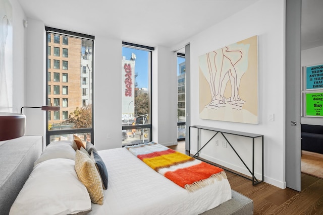 bedroom featuring a wall of windows, wood finished floors, access to outside, and multiple windows