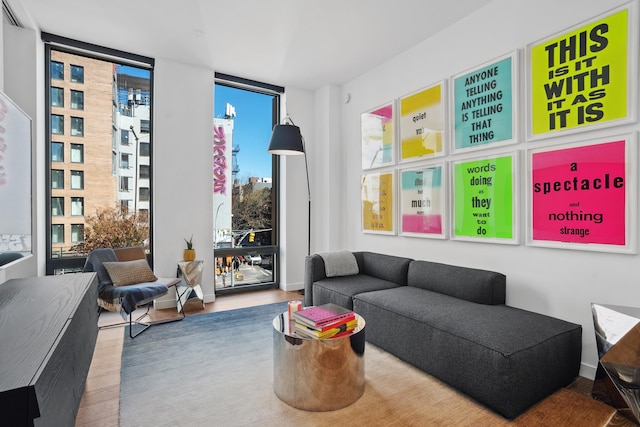 living area with baseboards, wood finished floors, and floor to ceiling windows