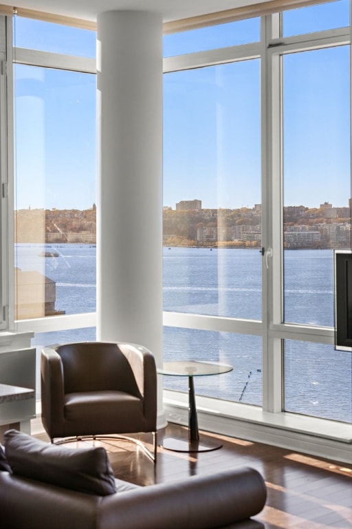 sitting room featuring expansive windows, a water view, and hardwood / wood-style floors