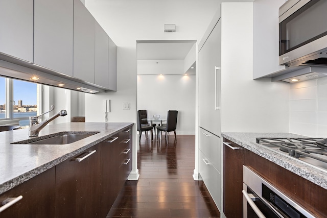 100 Riverside Blvd Unit 14-N, New York City, NY 10069 - kitchen featuring appliances with stainless steel finishes, a sink, modern cabinets, dark wood-type flooring, and light stone countertops