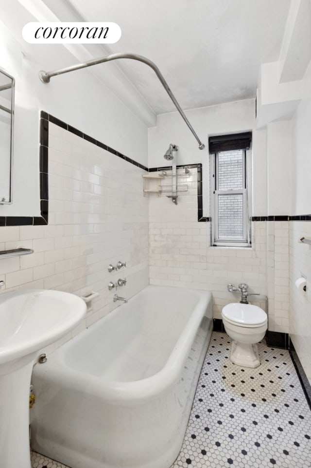 full bath featuring washtub / shower combination, tile patterned flooring, tile walls, and toilet