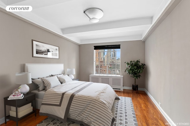 bedroom featuring baseboards, radiator heating unit, visible vents, and wood finished floors