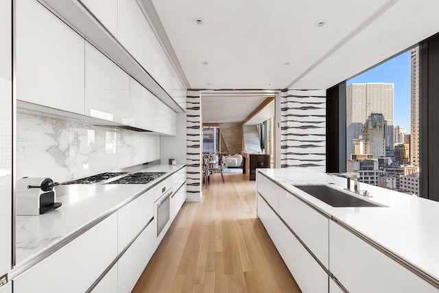 kitchen with light countertops, white cabinetry, a sink, and modern cabinets