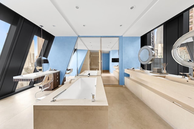 bathroom featuring finished concrete flooring, double vanity, a garden tub, and recessed lighting