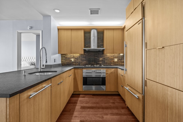 kitchen featuring stainless steel appliances, visible vents, a sink, wall chimney range hood, and a peninsula