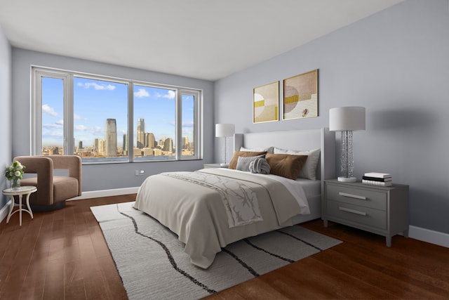 bedroom featuring baseboards, dark wood finished floors, and a city view