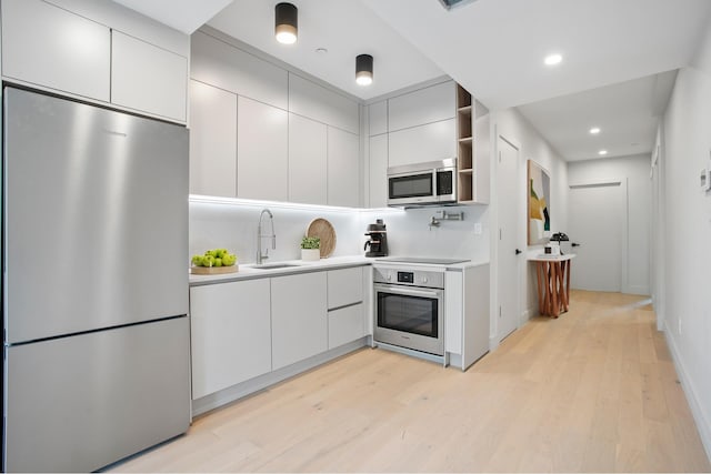 kitchen featuring open shelves, stainless steel appliances, light countertops, a sink, and modern cabinets