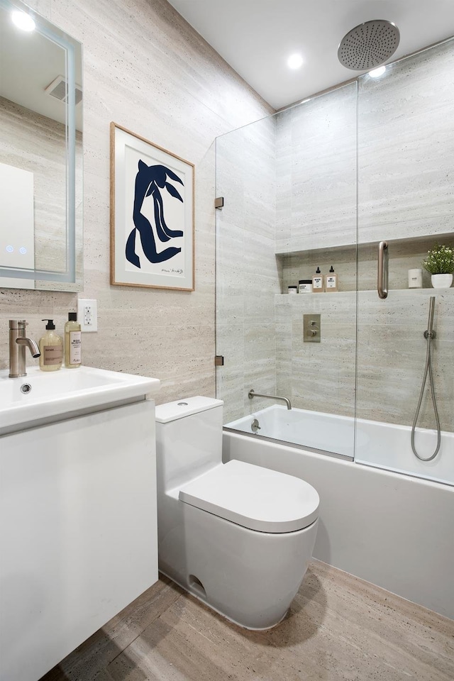 bathroom featuring visible vents, toilet, a combined bath / shower with rainfall shower, vanity, and wood finished floors