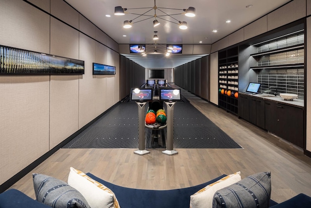 playroom featuring light wood-style floors, a bowling alley, and a chandelier