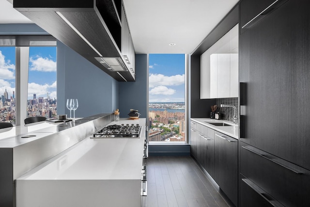 kitchen with a city view, stainless steel gas cooktop, a sink, modern cabinets, and dark cabinets