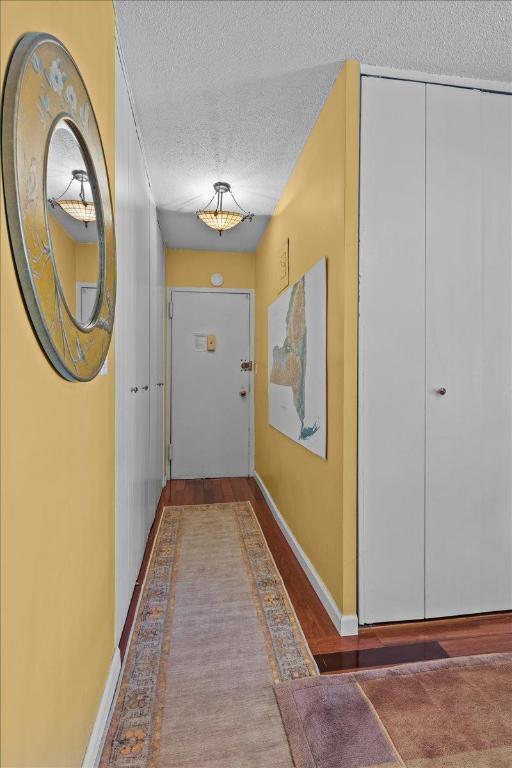 doorway to outside with dark wood-type flooring and a textured ceiling