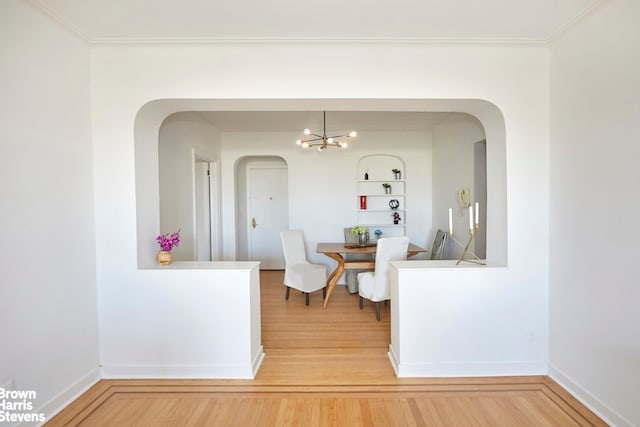 dining room featuring an inviting chandelier, hardwood / wood-style flooring, ornamental molding, and built in shelves