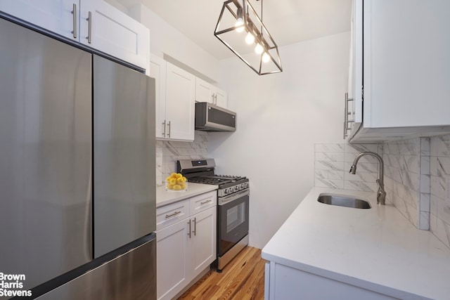 kitchen with stainless steel appliances, light countertops, white cabinets, and a sink