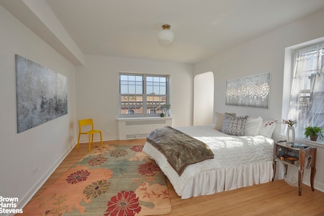 bedroom with radiator, baseboards, and wood finished floors