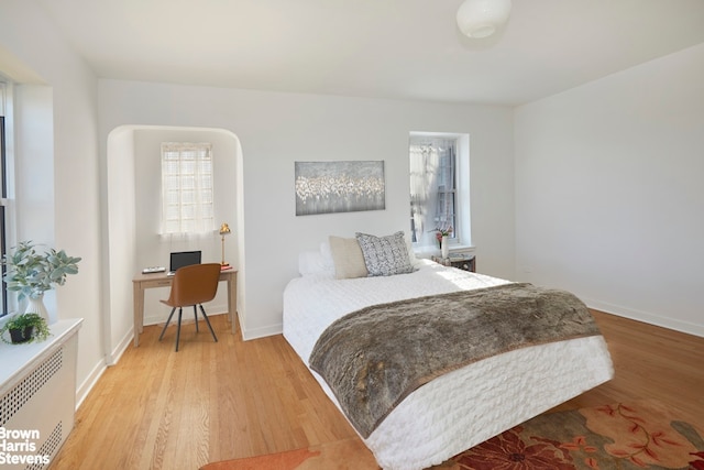 bedroom with baseboards, radiator heating unit, and wood finished floors