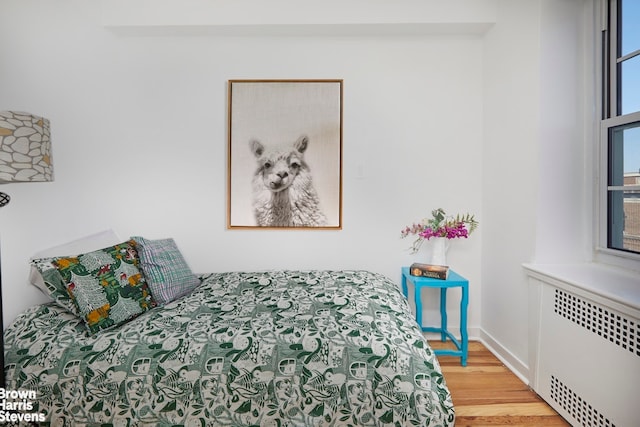 bedroom with radiator, baseboards, and wood finished floors