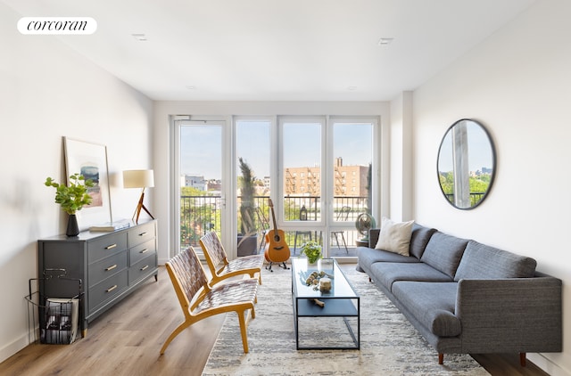 living room with baseboards, light wood-style flooring, visible vents, and a city view